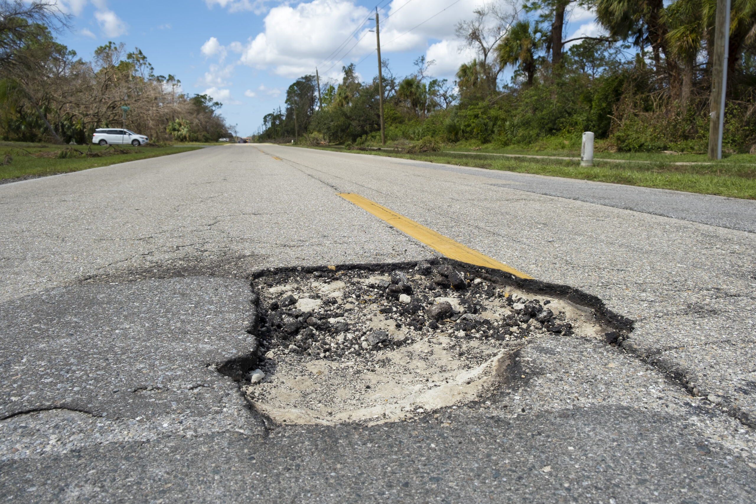 Damaged american road surface with deep pothole. Ruined street in urgent need of repair